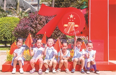幼兒園的小朋友在“我和國(guó)旗同框”的布景前拍照。